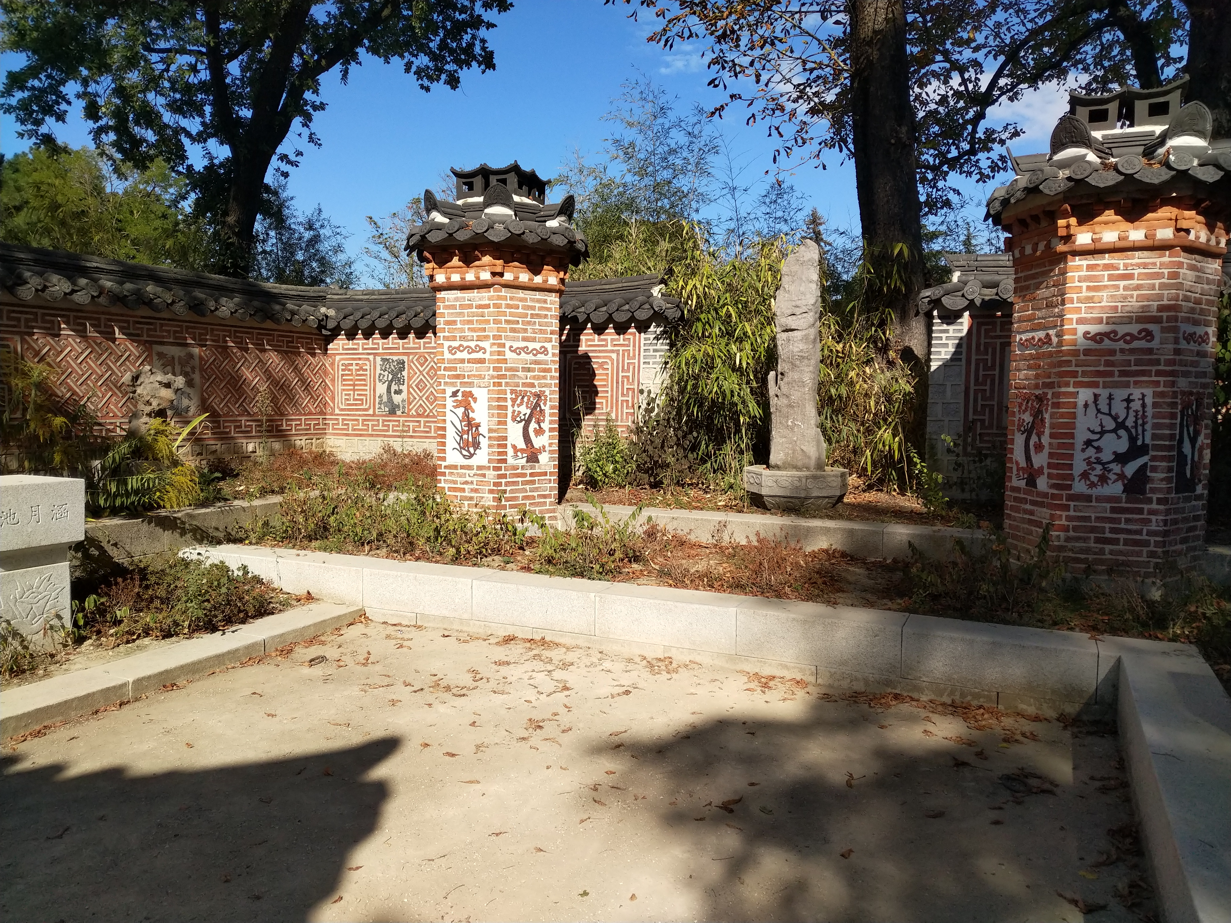 Koreanische Garten mit Hochbeeten und einer kleinen Anordnung von Säulen und einer Statue.